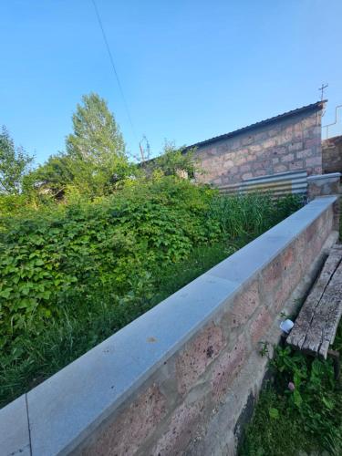 a brick wall with a sidewalk next to a hedge at Manan Guesthouse in Chʼkalovka