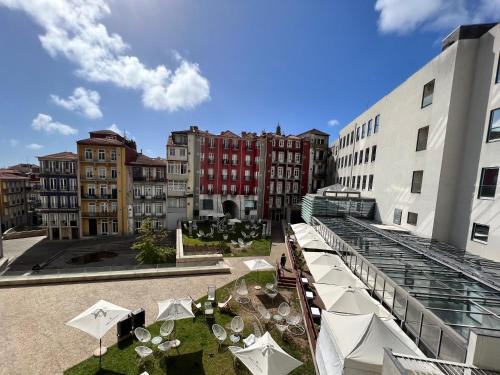 a courtyard with tables and white umbrellas in a city at New Oporto Apartments - São Bento in Porto