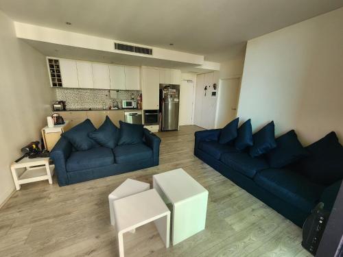 a living room with two blue couches and a kitchen at One bedroom apartment in Docklands in Melbourne