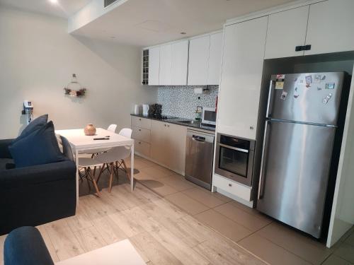 a kitchen with a stainless steel refrigerator and a table at One bedroom apartment in Docklands in Melbourne