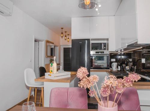 a kitchen with white cabinets and pink chairs in it at Apartment Matko in Ploče