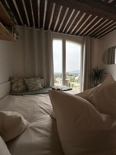a large bed in a room with a large window at Appartement Duplex Le Mimosa Parking a proximité vue exceptionnelle in Grasse