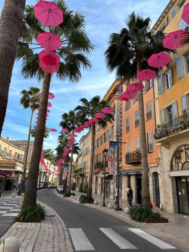a street with palm trees and pink umbrellas at Appartement Duplex Le Mimosa Parking a proximité vue exceptionnelle in Grasse