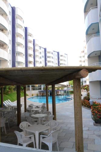 a patio with white tables and chairs and buildings at Prime Hotel Águas da Serra in Rio Quente