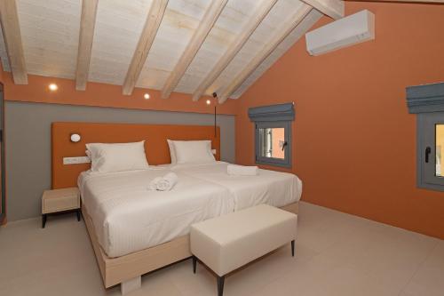 a bedroom with a white bed and orange walls at Tessera Villas & Studios Collection in Gouvia