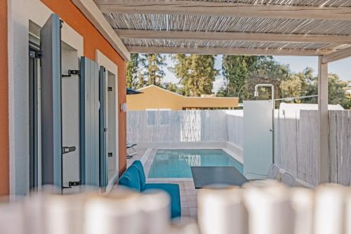 a house with a swimming pool and a fence at Tessera Villas & Studios Collection in Gouvia