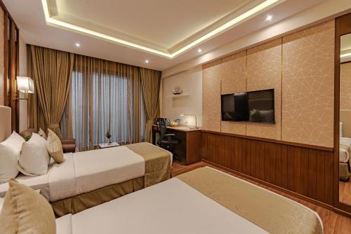 a hotel room with two beds and a flat screen tv at Goldfinch Hotel Mangalore in Mangalore