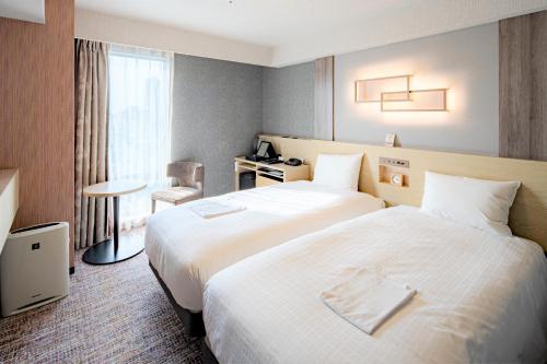 a hotel room with two beds and a window at Richmond Hotel Akita Ekimae in Akita