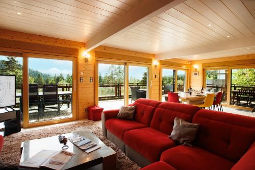un salon avec un canapé rouge et une table dans l'établissement Chalet d’exception avec sauna, jacuzzi, ping-pong, à Liézey