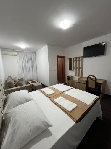 a bedroom with a large white bed and a couch at Motel Aura in Mostar