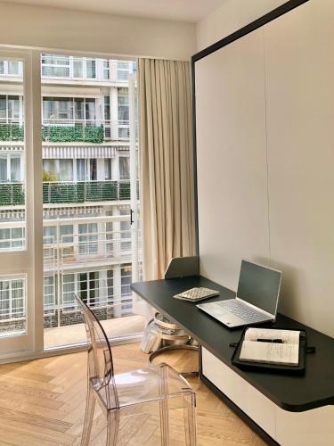 un bureau avec un bureau, un ordinateur portable et une fenêtre dans l'établissement Studio confort et design Etoile-Neuilly-La Défense, à Neuilly-sur-Seine