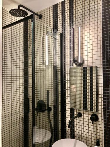 La salle de bains est pourvue de carrelage noir, d'une douche et d'un lavabo. dans l'établissement Studio confort et design Etoile-Neuilly-La Défense, à Neuilly-sur-Seine