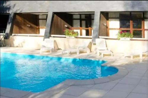- une piscine avec des chaises blanches à côté d'une maison dans l'établissement Superbe Appart 4 Pers Saint Lary, à Saint-Lary-Soulan