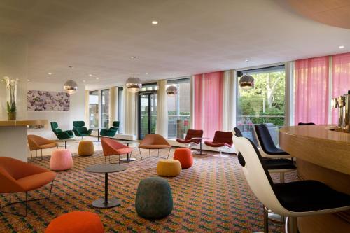 a lobby with colorful chairs and tables and windows at Hotel Dolce La Hulpe Brussels in La Hulpe