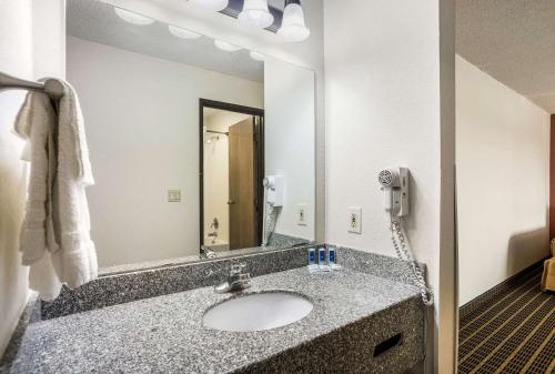 a bathroom with a sink and a mirror at Rodeway Inn Cedar Rapids Westdale in Cedar Rapids