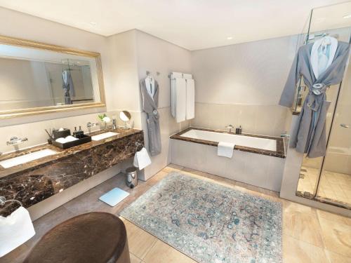 a bathroom with a tub and two sinks and a bath tub at Southern Sun The Cullinan in Cape Town