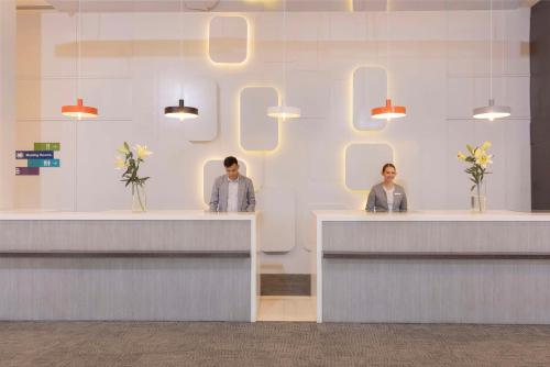 two people sitting at reception desks in a lobby at Park Inn By Radisson Iloilo in Iloilo City