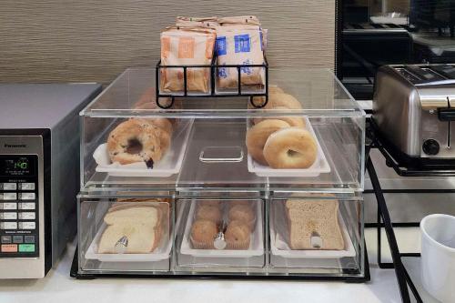 a display case with donuts on a counter next to a microwave at Comfort Inn & Suites Shepherdsville - Louisville South in Shepherdsville