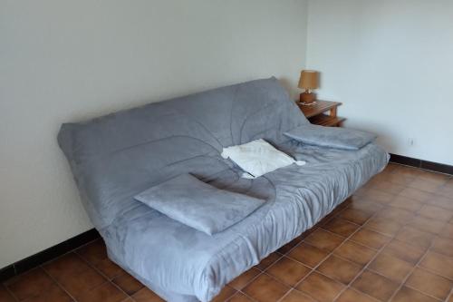 - un canapé gris dans une chambre dotée de carrelage dans l'établissement Pleasant studio near the sea, à Cavalaire-sur-Mer