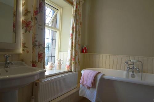 a bathroom with a tub and a sink and a window at Peak District Luxury cottage, sleeps 8 plus pets in Tideswell