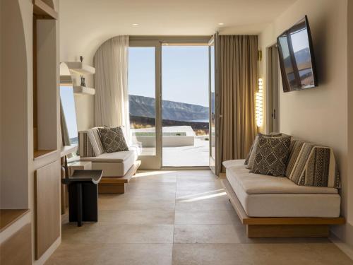 a living room with two couches and a television at Santo Mine Oia Suites in Oia