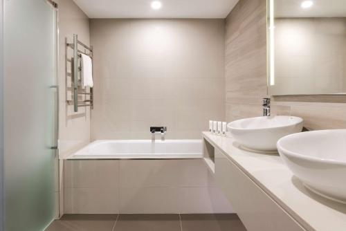 a white bathroom with a tub and a sink at Vibe Hotel Subiaco Perth in Perth