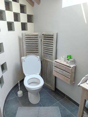 a bathroom with a white toilet in a room at Sous les toits in Dosches