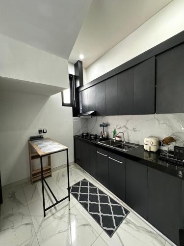 eine Küche mit schwarzen Schränken, einem Waschbecken und einem Tisch in der Unterkunft Ramana Villa Uluwatu in Uluwatu