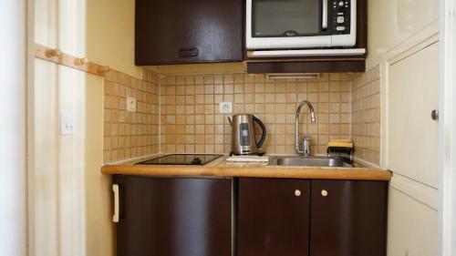 une petite cuisine avec un évier et un micro-ondes dans l'établissement Rue de Longchamp - Paris 16, à Paris