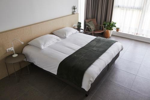 a bedroom with a large bed with white sheets and pillows at Het Kasterhuis in Wetteren