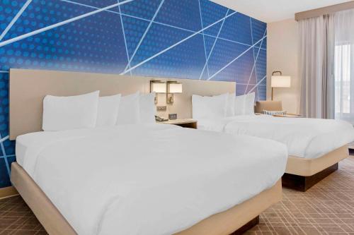 two beds in a hotel room with blue walls at Comfort Inn & Suites Rapid City near Mt Rushmore in Rapid City