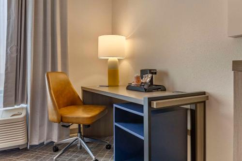a desk with a lamp and a chair in a room at Comfort Inn & Suites Rapid City near Mt Rushmore in Rapid City