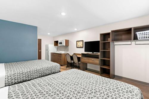 a bedroom with two beds and a desk with a computer at WoodSpring Suites Indio - Coachella Valley in Indio