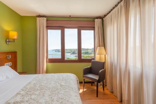 a bedroom with a bed and a chair and a window at La Colina in Gijón
