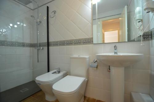 ein Badezimmer mit Toilette, Waschbecken und Spiegel in der Unterkunft Playa Canela PREMIUM & SOLMARES in Punta del moral