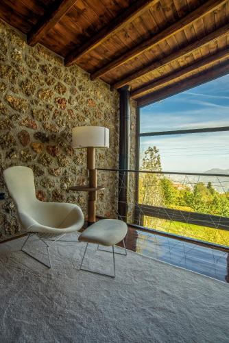 a chair and a lamp in a room with a large window at Heartbeat Mountain Escapes in Kato Trikala Korinthias