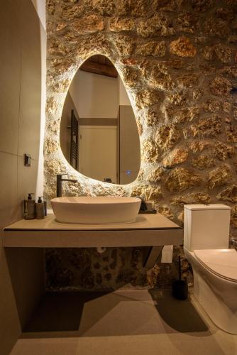 a bathroom with a sink and a mirror on a stone wall at Heartbeat Mountain Escapes in Kato Trikala Korinthias