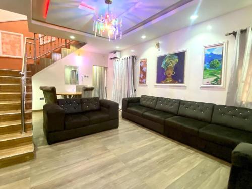 a living room with a black couch and a chandelier at Supreme 3-BED-Duplex With 24HRS PWR & FREE Wi-Fi in Lagos