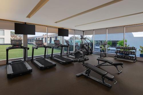 a gym with a row of treadmills and elliptical machines at Indore Marriott Hotel in Indore
