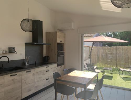 une cuisine et une salle à manger avec une table et des chaises dans l'établissement VIDAGO maison neuve tout confort avec terrasse privée, à Nieul-sur-Mer