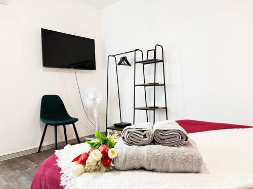 - une chambre avec un lit, des serviettes et des fleurs dans l'établissement Le London, studio proche aéroport, à Saint-Louis