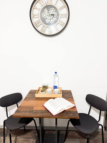 une table avec deux chaises et une horloge sur le mur dans l'établissement Le London, studio proche aéroport, à Saint-Louis