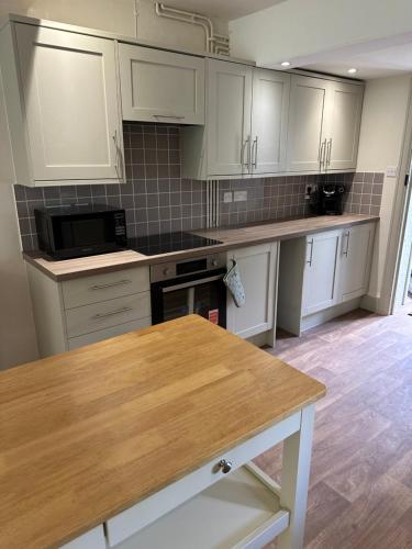 a kitchen with white cabinets and a wooden table at The Stud House at Danebury in Stockbridge