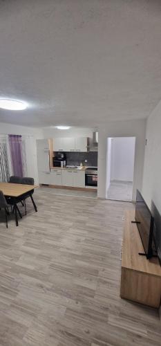 an empty living room with a table and a kitchen at Guest House Laura in Korenica