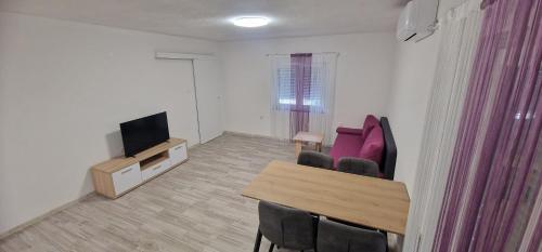 a living room with a table and chairs and a television at Guest House Laura in Korenica