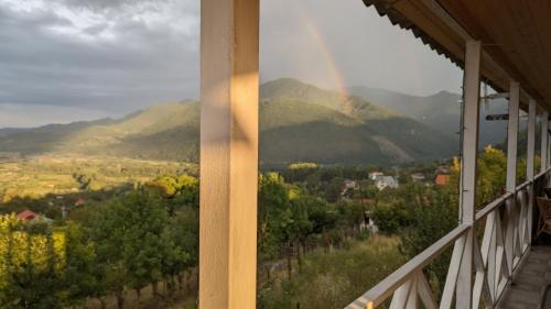 a view from a porch with a rainbow in the distance at Mountaintop hostel apartments - Hostel Kvish^Khedi in K'vishkhet'i