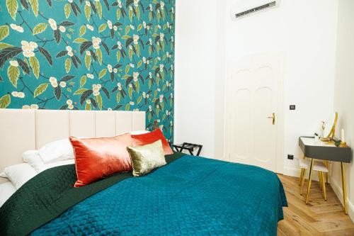 a bedroom with a bed with a blue comforter and floral wallpaper at Kárász16 Apartman Szeged in Szeged