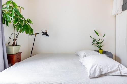 - une chambre avec un lit blanc et 2 plantes dans l'établissement GuestReady - Cosy stay near Jardin du Luxembourg, à Paris