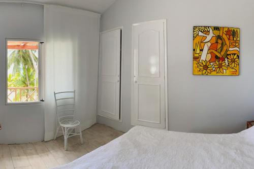 a bedroom with a bed and a chair and a window at Beachfront Villa Miramar in Pointe d'Esny