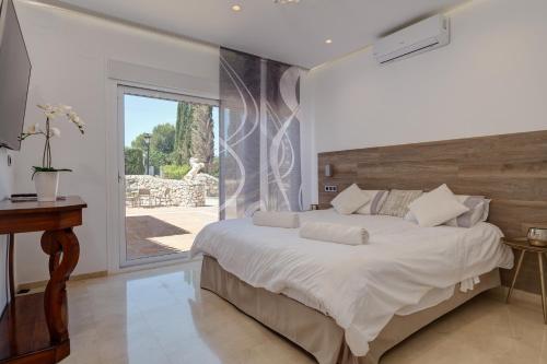 a bedroom with a large bed and a sliding glass door at Villa Vista Verde Mijas Golf - Luxury with Optional heated pool & jacuzzi in Mijas